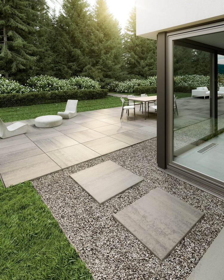 Modern backyard with large-format Techo-Bloc Industria 900 slabs used for the patio and stepping stones, surrounded by greenery, gravel accents, and minimalist outdoor furniture.