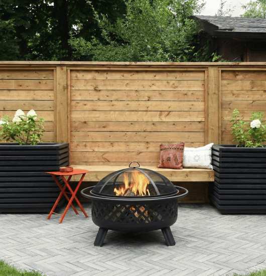 Portable fire pit sitting on Techo-Bloc's Westmount pavers in a small backyard