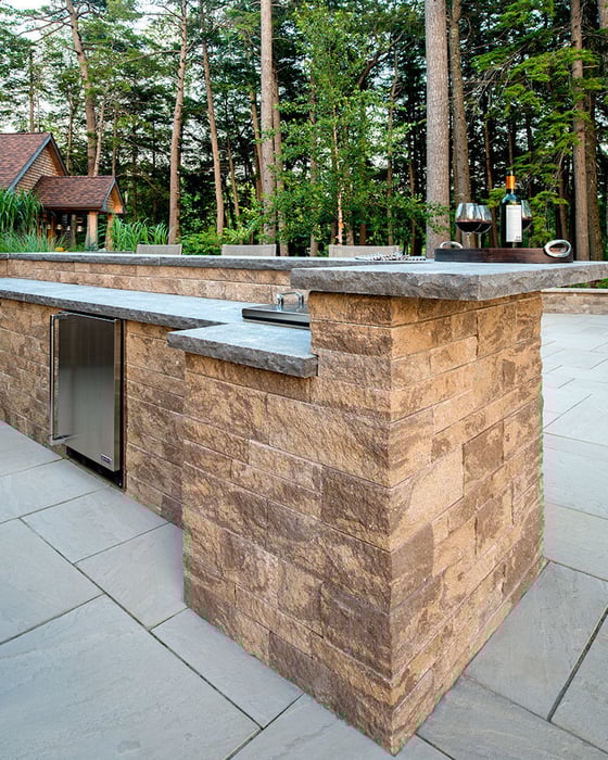 Outdoor kitchen with Techo-Bloc's Mini-Creta Architectural retaining wall and a stone countertop